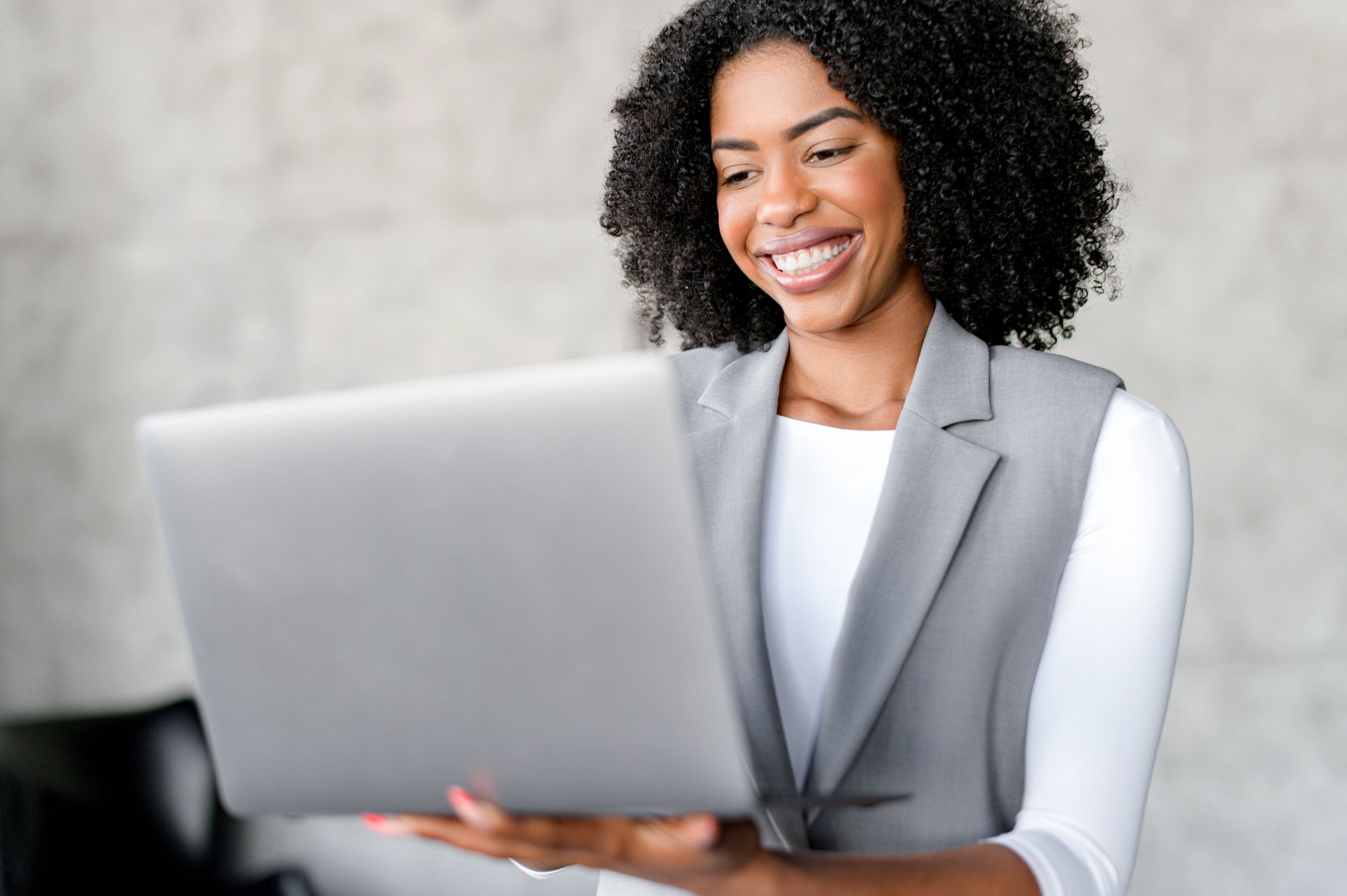 A professional African-American businesswoman beams with confidence as she holds her lapto